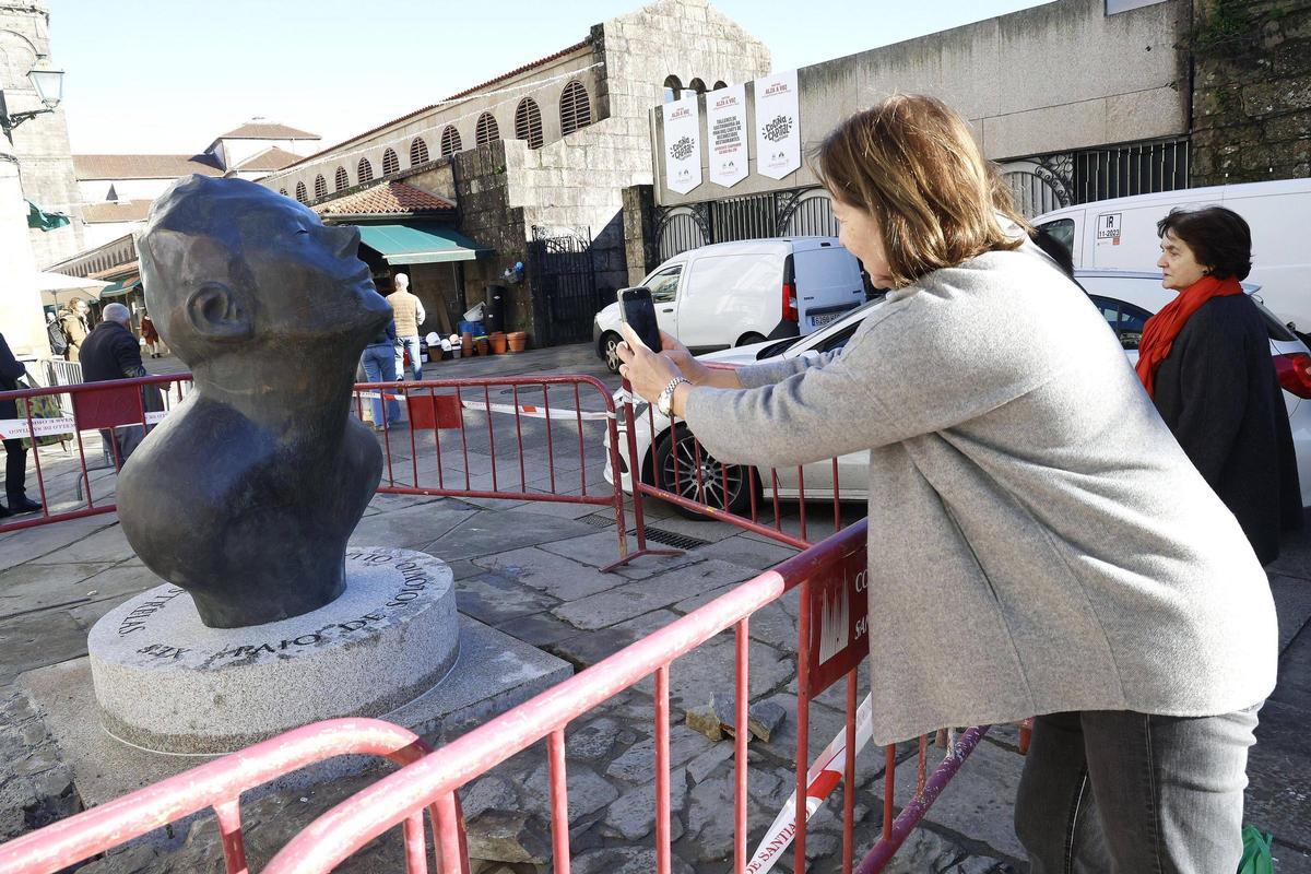 Una persona fotografía la pieza situada ante la Iglesia de San Fiz de Solovio