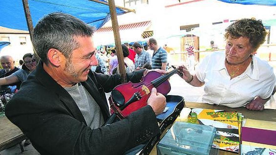 Gaspar Medina y Buenaventura Montes se interesan por un violín en el mercado del trueque de Laviana.