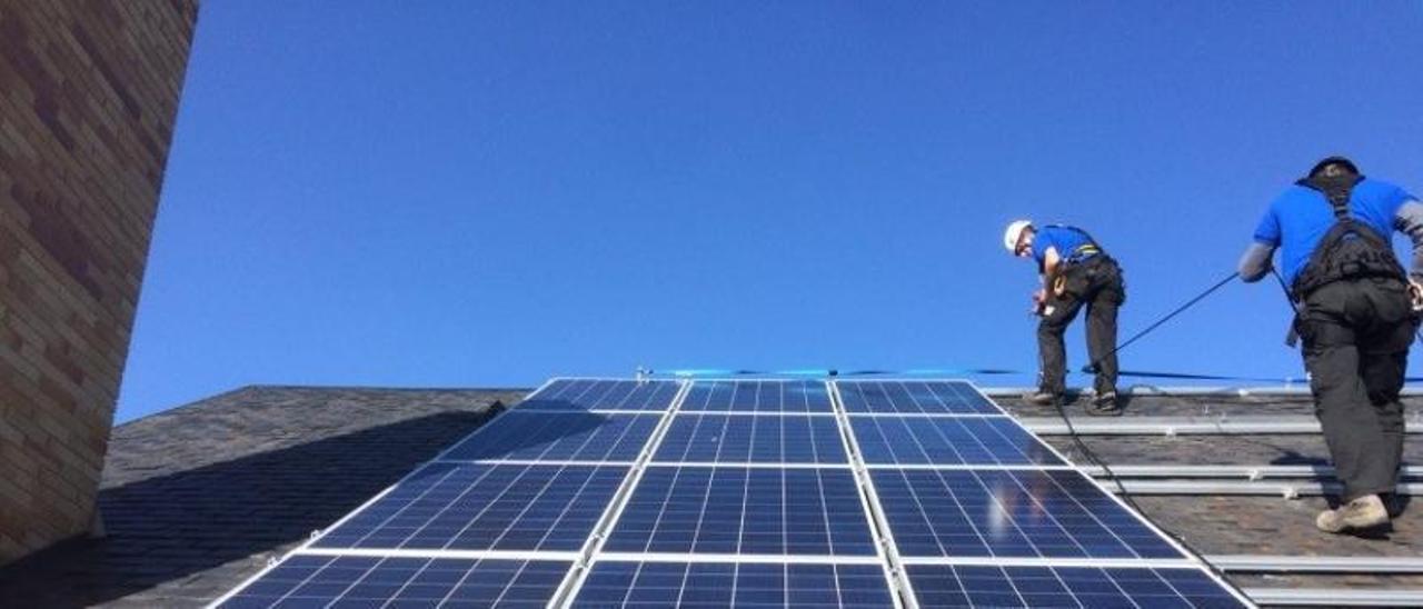 Instaladores de placas solares trabajan en la cubierta de un edificio.