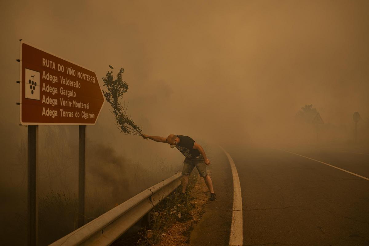 Un hombre combate un incendio forestal con una rama en Cualedro. Cuando los recursos son insuficientes, los vecinos utilizan todo lo que tienen a mano para extinguir las llamas, incluidas ramas, herramientas agrícolas y mangueras de agua. Ourense, Galicia, España, 15 de agosto de 2025.