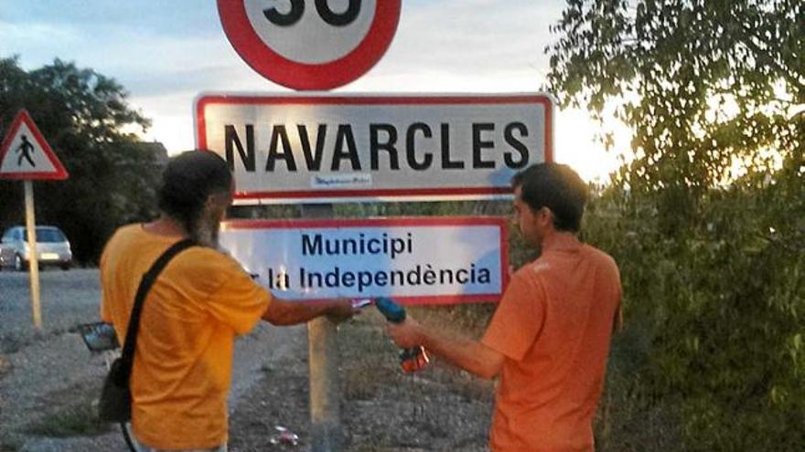 Dos integrants de la CUP col·locant el rètol a l&#039;entrada del poble