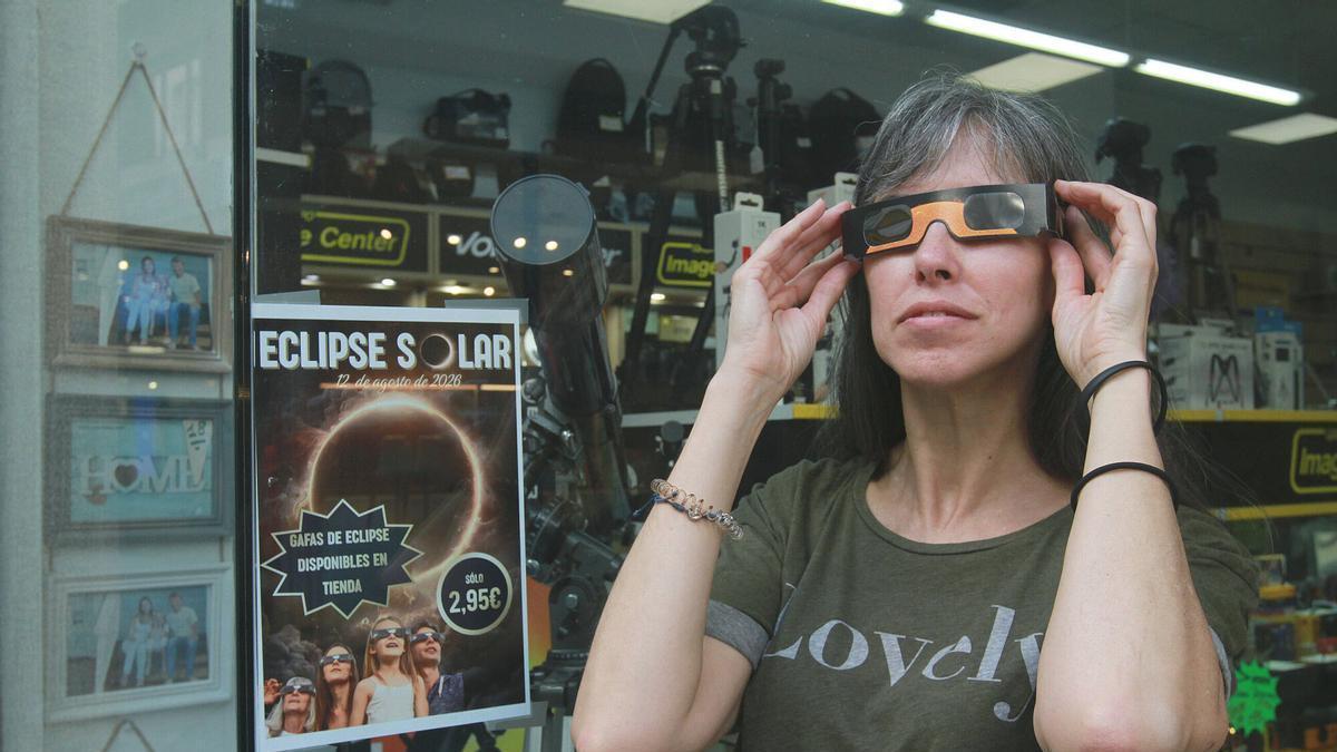 Una mujer prueba gafas para el eclipse en una tienda de Ourense.