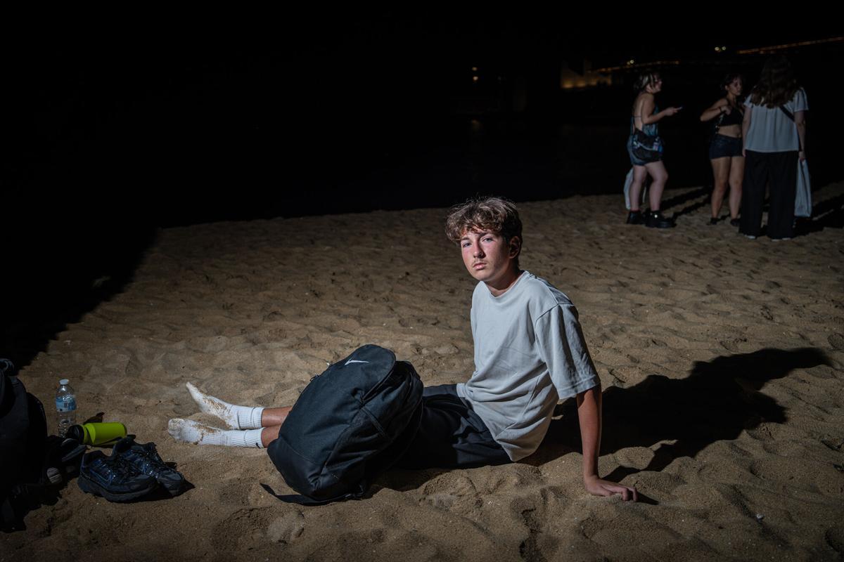 Clément, de 18 años y natural de París, durante la entrevista. El joven francés pasará su segunda noche en las playas de Barcelona para evitar el coste del alojamiento durante su estancia en la ciudad. A 6 de agosto de 2026. Sociedad. AUTOR: MANU MITRU