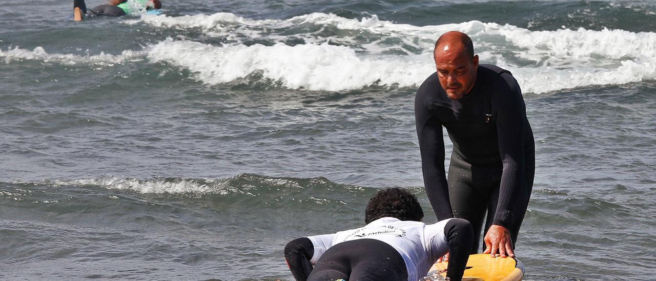 El monitor Lucas García, con uno de los participantes. En el círculo, parte de los asistentes a la prueba de surf adaptado. Abajo, de izquierda a derecha, Marcos Tapia, Ángel Luis Curiel, Christian Alonso, Joseba Mercader, Paloma Oñate, Carmen López, Iván Espárrago, Álvaro Menéndez y María Martín-Granizo. | M. Villamuza