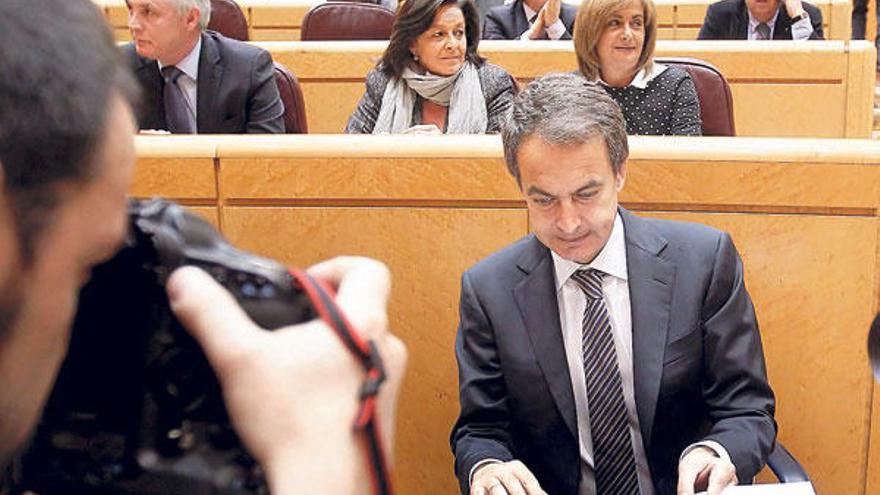 Zapatero repasa unas notas antes de intervenir, ayer, en el Senado; detrás de él y a la derecha, la senadora viguesa Carmela Silva. // Efe