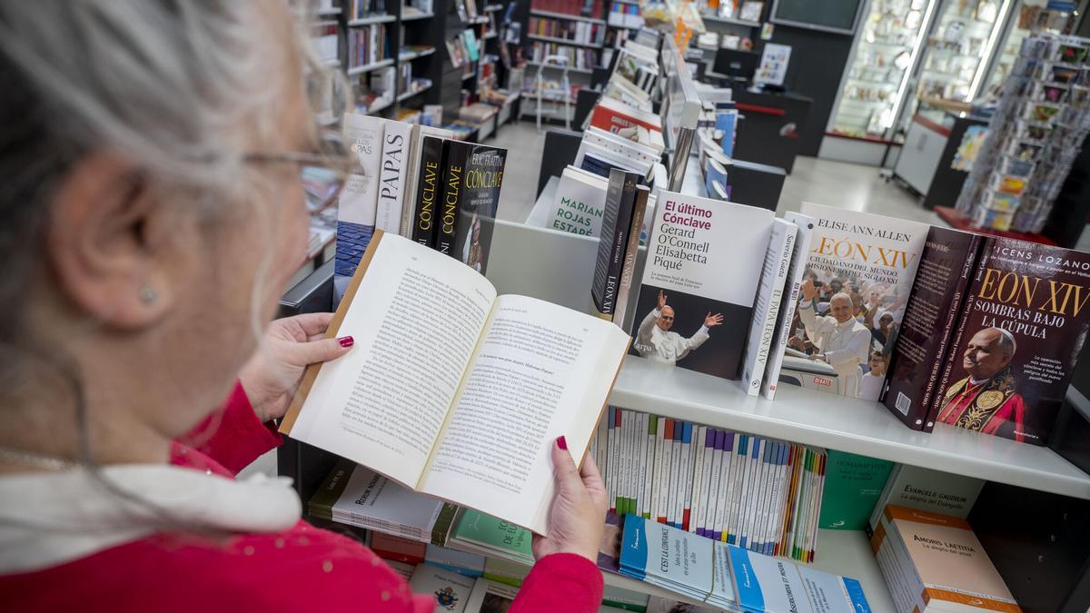 Dependienta de la Llibreria Paulines mostrando el interior de una biografía de León XIV.
