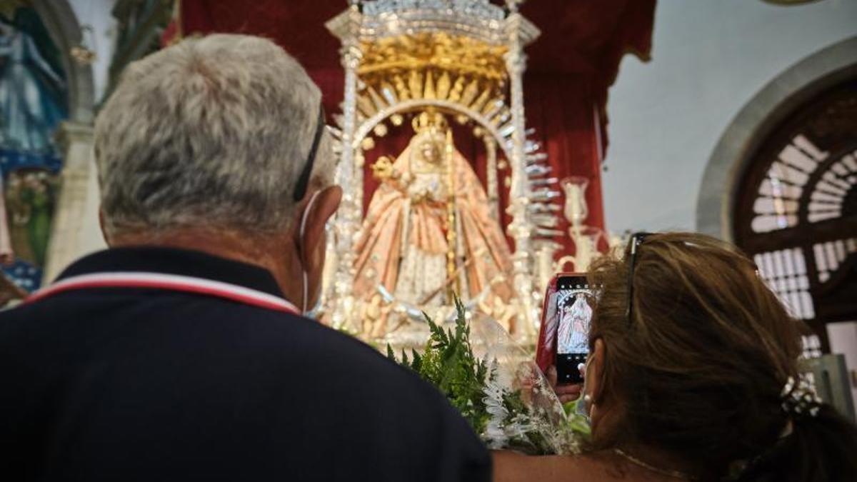 Dos personas rezan ante la Virgen de Candelaria.