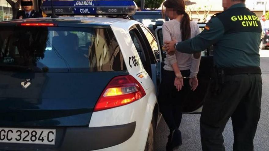 Una de las detenidas es introducida en el coche de la Guardia Civil.