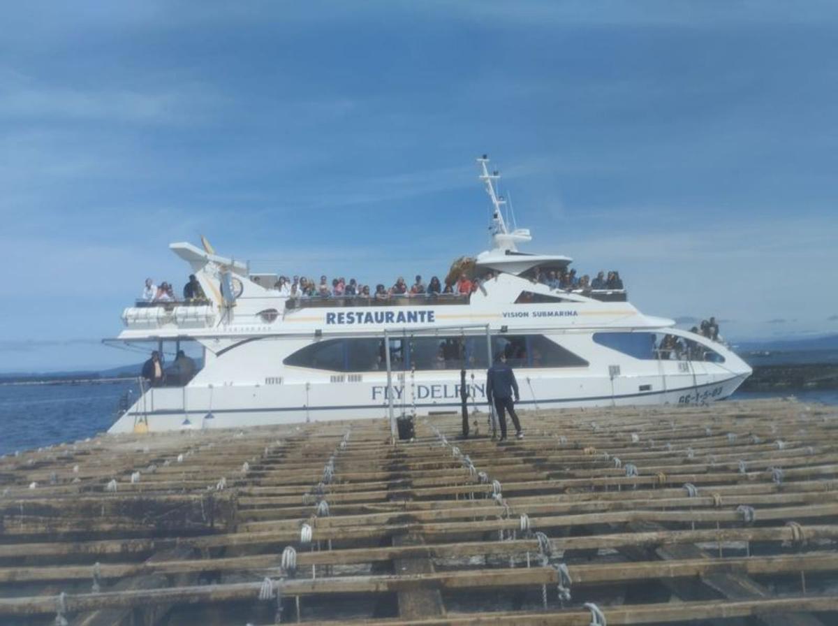 Turistas a bordo de un catamaránabarloado a una batea para mostrarlessu funcionamiento, ayer .   | //  FDV