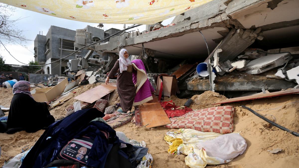 Una mujer recoge enseres de su casa en la franja de Gaza derribada en los ataques de estas últimas semanas.
