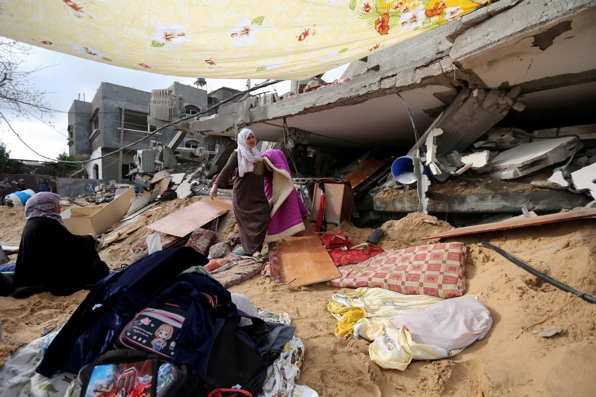 Una mujer recoge enseres de su casa en la franja de Gaza derribada en los ataques de estas últimas semanas.