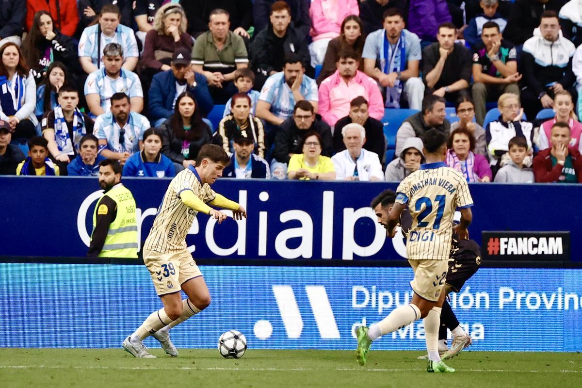 Pedrola, apoyado por Jonathan Viera, conduce un balón en La Rosaleda