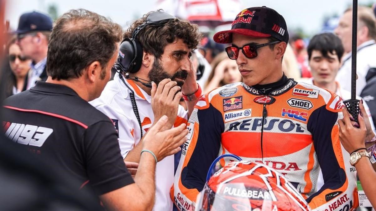 Emilio Alzamora, a la izquierda, Santi Hernández, con barba, y Marc Márquez maquina la estrategia a seguir en la misma parrilla de salida del GP de Brno,