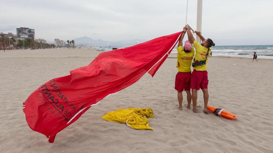 Socorristas izando la bandera roja en la playa de San Juan esta tarde después de que la Policía Local se la entregara.