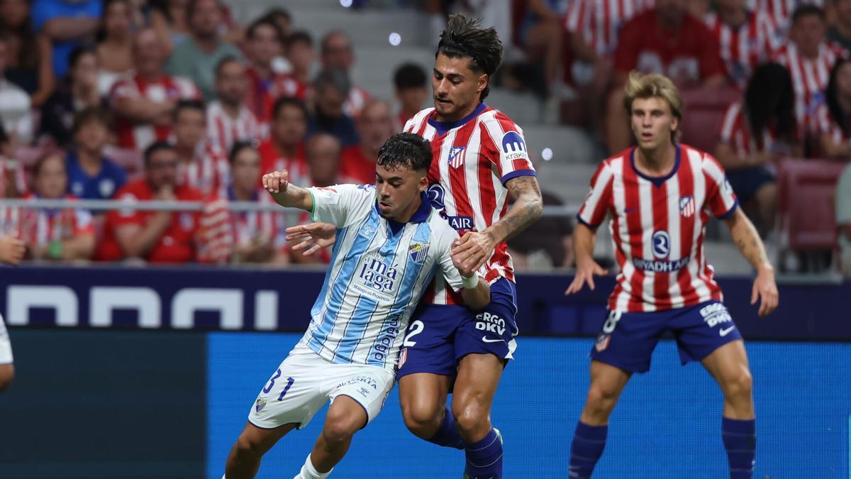 MADRID, 19/08/2026.- El defensa del Atlético de Madrid Carlos Martín (c) lucha con Rafa Garrido (i), del Málaga CF, durante el partido de la primera jornada de LaLiga que Atlético de Madrid y Málaga CF disputan este miércoles en el estadio Metropolitano. EFE/Kiko Huesca