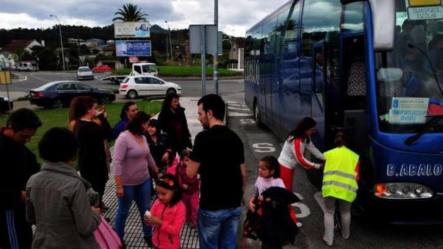 Varios de los niños y sus madres a su regreso del colegio ayer en la parada sin marquesina.  // Iñaki Abella