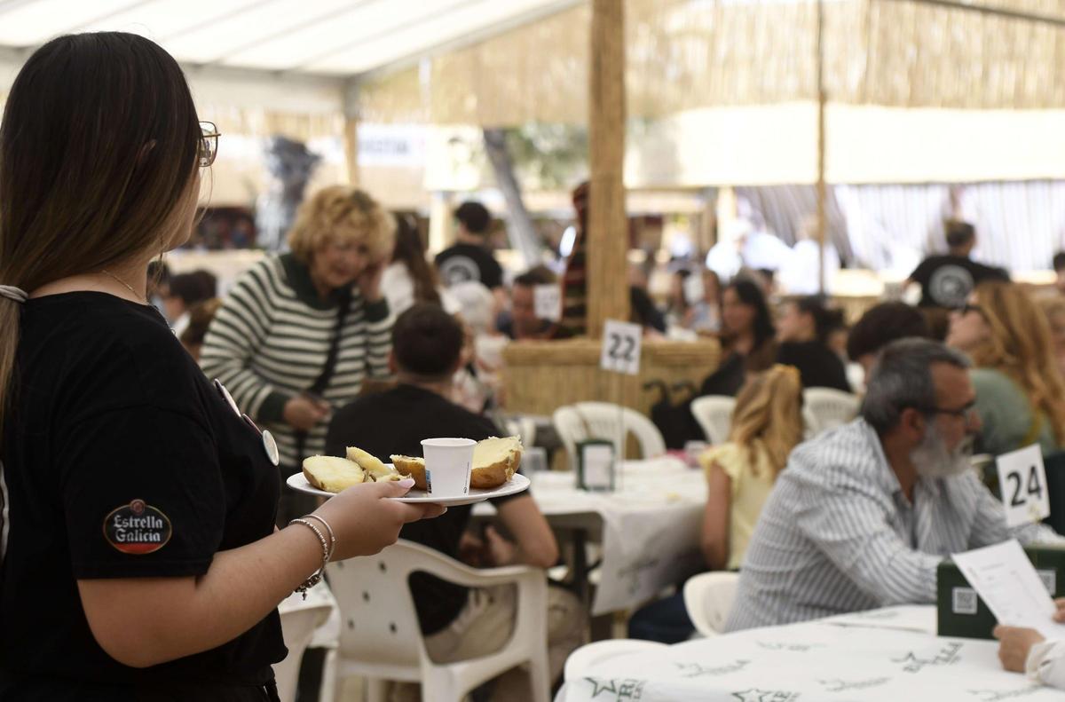 Una camarera lleva comida a una de las mesas durante la apertura de las barracas.
