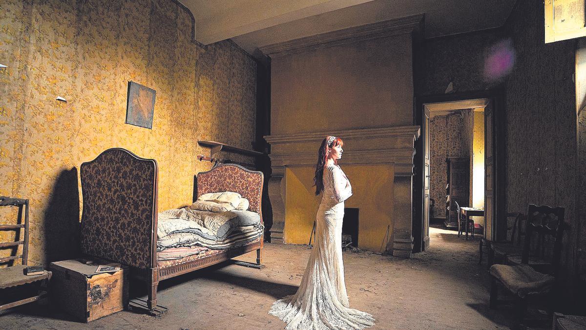 Una model vestida de núvia posa en una habitació.