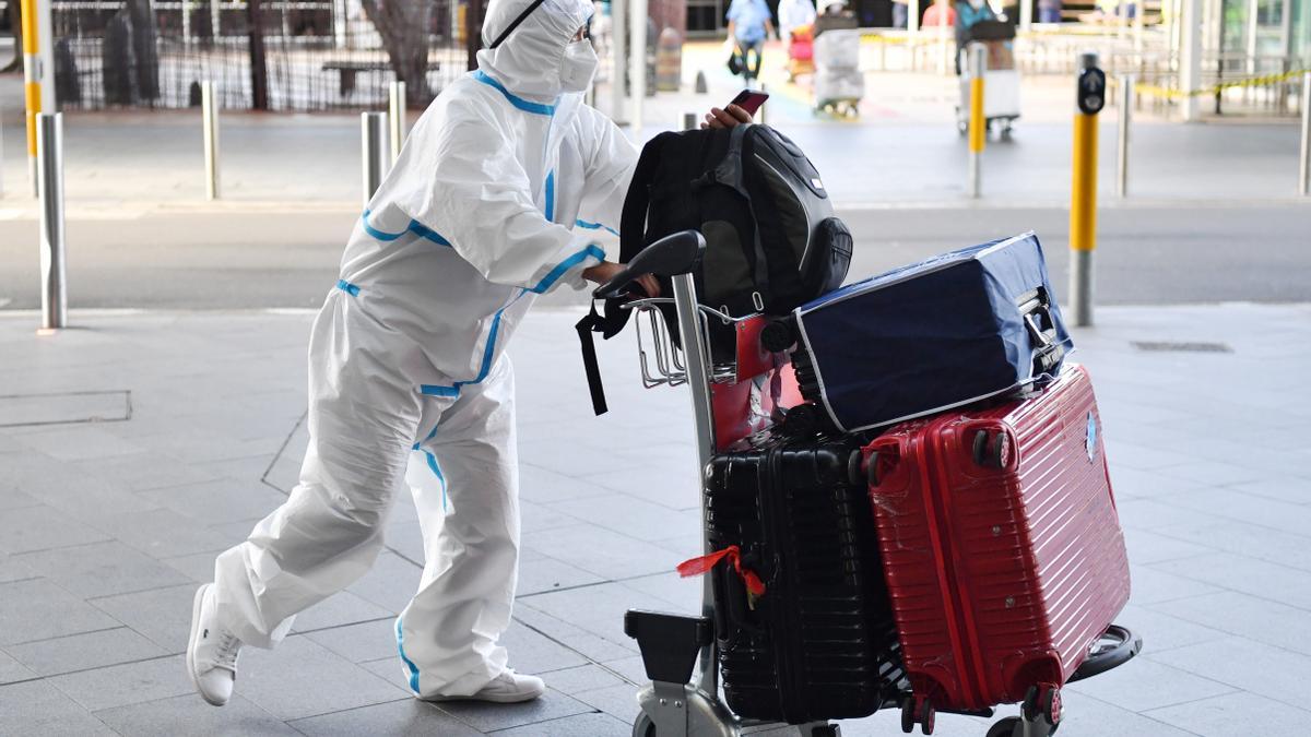 Un viajero viste un traje protector a su llegada al aeropuerto de Sídney, en Australia obligan a usar mascarillas al aire libre