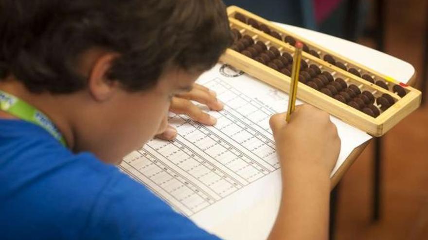 Un niño realiza operaciones matemáticas con ayuda de un ábaco. / aloha