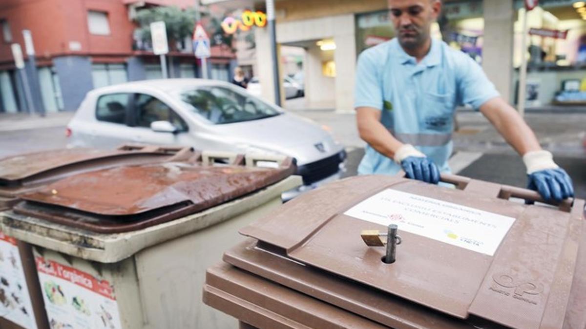 Un operario instala los nuevos contenedores con candado para supermercados, el lunes, en Girona.