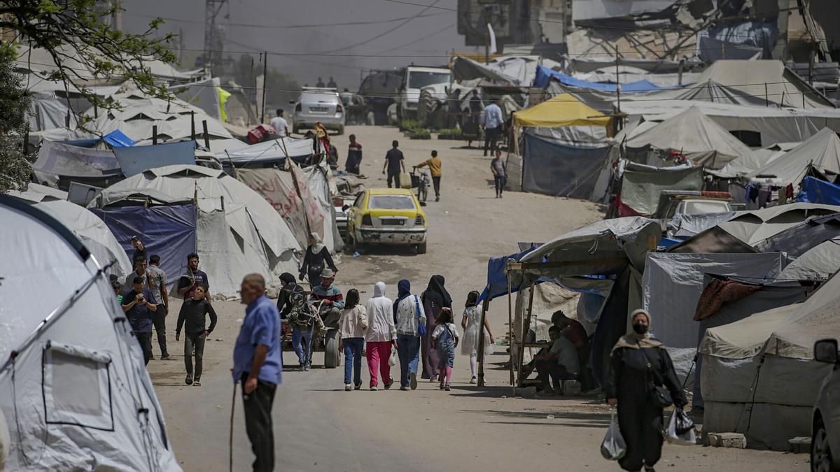 Desplazados internos palestinos se mueven entre tiendas de campaña en la carretera de Al Jalaa, en el centro de la ciudad de Gaza.
