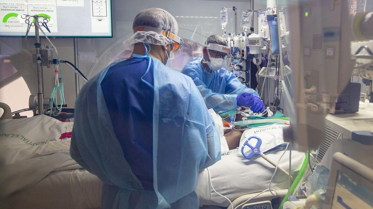 Un sanitario asiste a un enfermo de covid-19, en la UCI del Hospital Clínic de Barcelona Foto de Julio Carbó