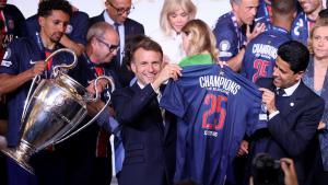 El presidente francés, Emmanuel Macron y el presidente catarí del Paris Saint-Germain, Nasser al-Khelaifi sostienen una camiseta del equipo parisino durante la recepción en el Palacio del Elíseo en París.
