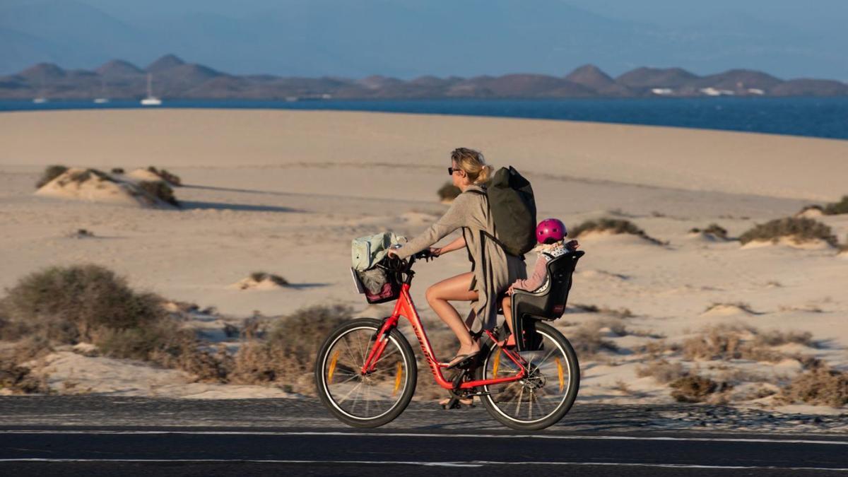 Una turista pasea en bici junto a las playas de Corralejo.