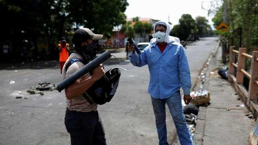 Dos enmascarados hacen guardia ante un refugio de manifestantes. // Reuters