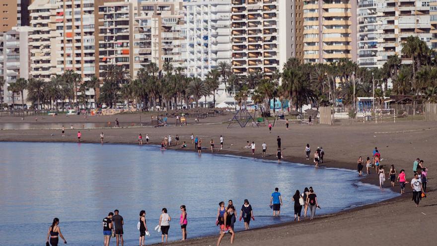 Numerosas personas caminan por la orilla de la playa de la Malagueta de Málaga.