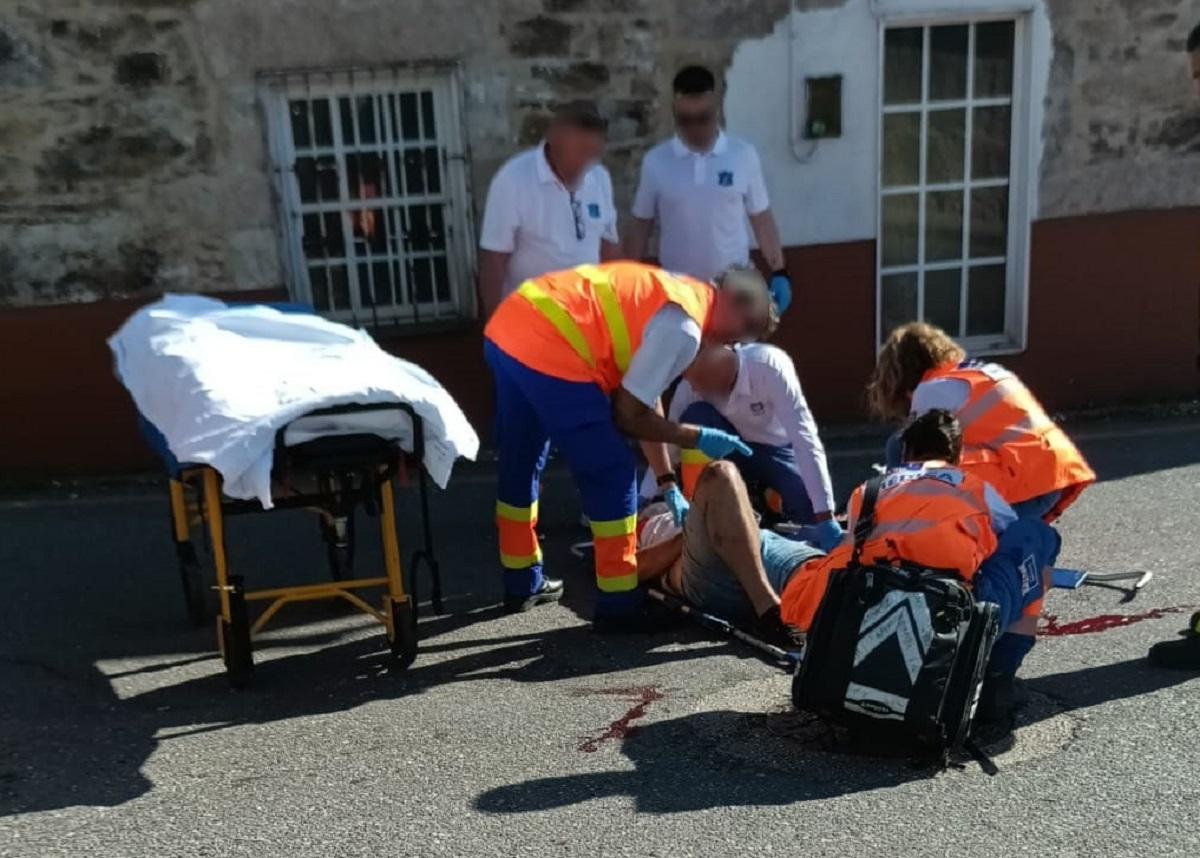 Los sanitarios atienden al motorista, con una herida abierta en la pierna, tras el accidente en San Paio
