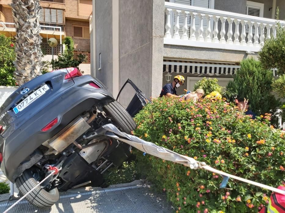 Dos ocupantes de un vehículo han sido rescatados por los bomberos de Alicante tras quedar su coche suspendido entre una palmera y una pared en el acceso de una urbanización de Alicante.