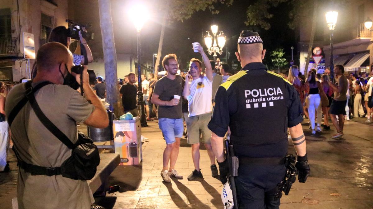 Un agent de la Guàrdia Urbana de Barcelona davant de persones fent &#039;botellón&#039; al passeig del Born durant el desallotjament de l&#039;espai, en la cinquena onada de la Covid-19 a Catalunya