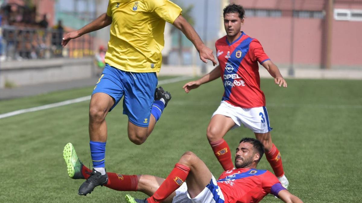 Joaquín, goleador amarillo ayer, salta para salvar la entrada de Adrián Machín, del Lanzarote; detrás Cedenilla. | | UDLP