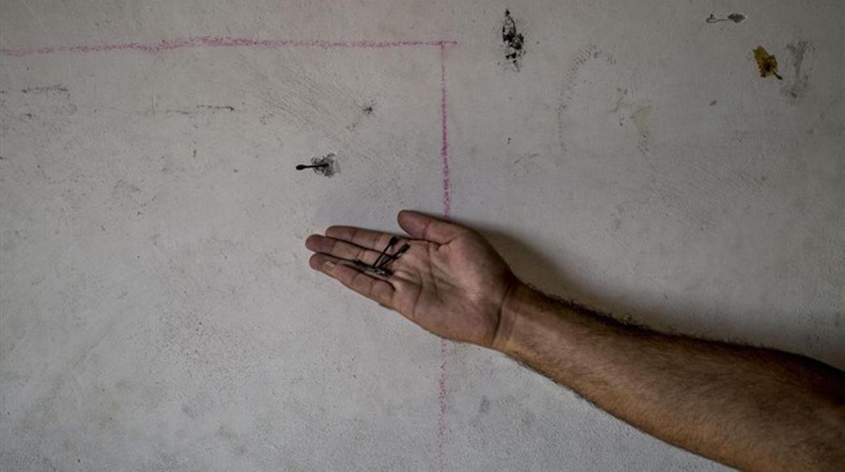 Un palestino del campo de refugiados de Bureij en la Franja de Gaza sostiene en la palma de su mano algunos dardos, como el que se ve atrapado en la pared de su casa.