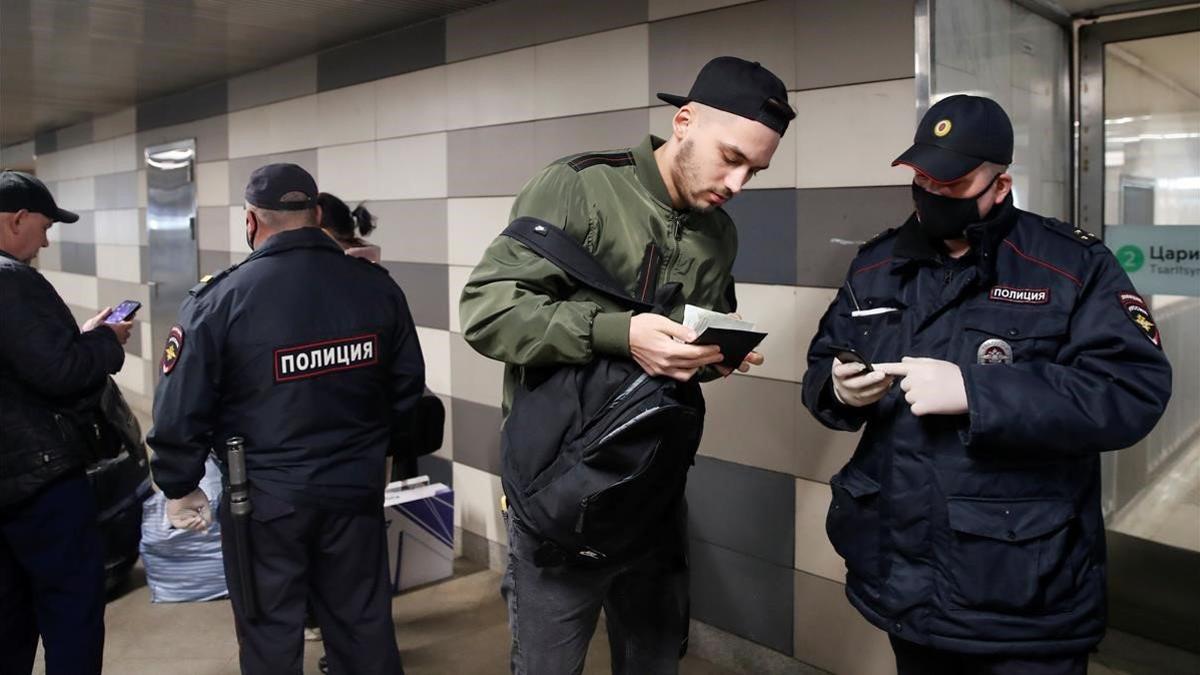 Agentes con máscaras vigilan las entradas en una estación de metro de Moscú.