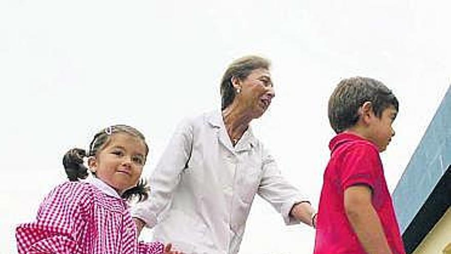 Una maestra acompaña a dos niños el primer día del curso pasado, en Avilés.