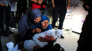 Una mujer palestina sostiene el cuerpo amortajado de un niño muerto tras un bombardeo israelí, en una clínica de salud en Rafah.