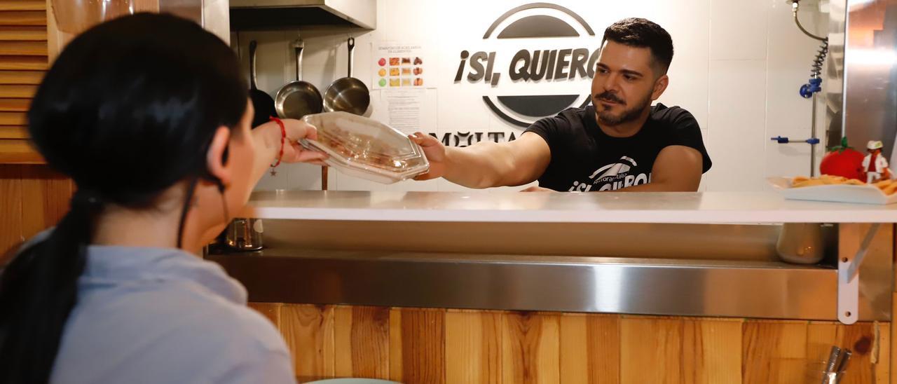 Un empleado de un restaurante entrega a un cliente comida para llevar a casa.