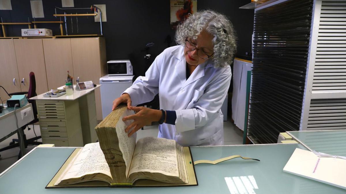 Una trabajadora del Archivo Municipal de Córdoba con uno de los tomos.