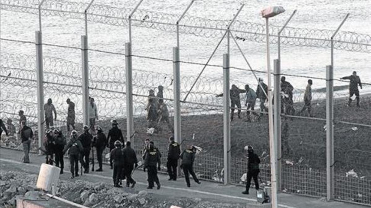 La policía trata de contener a un grupo de inmigrantes, ayer en la valla junto a la playa de Tarajal.