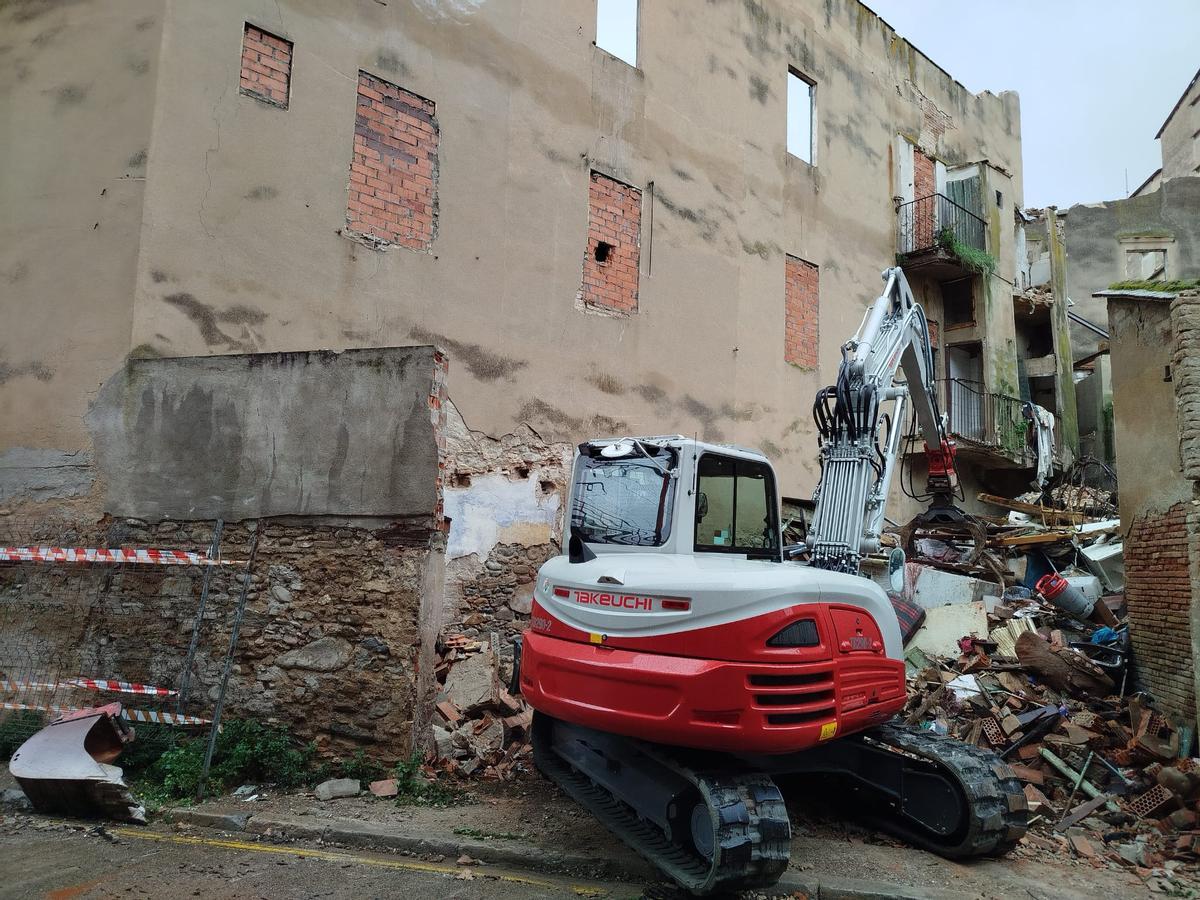Una màquina amb part de l'edifici ja enderrocat.