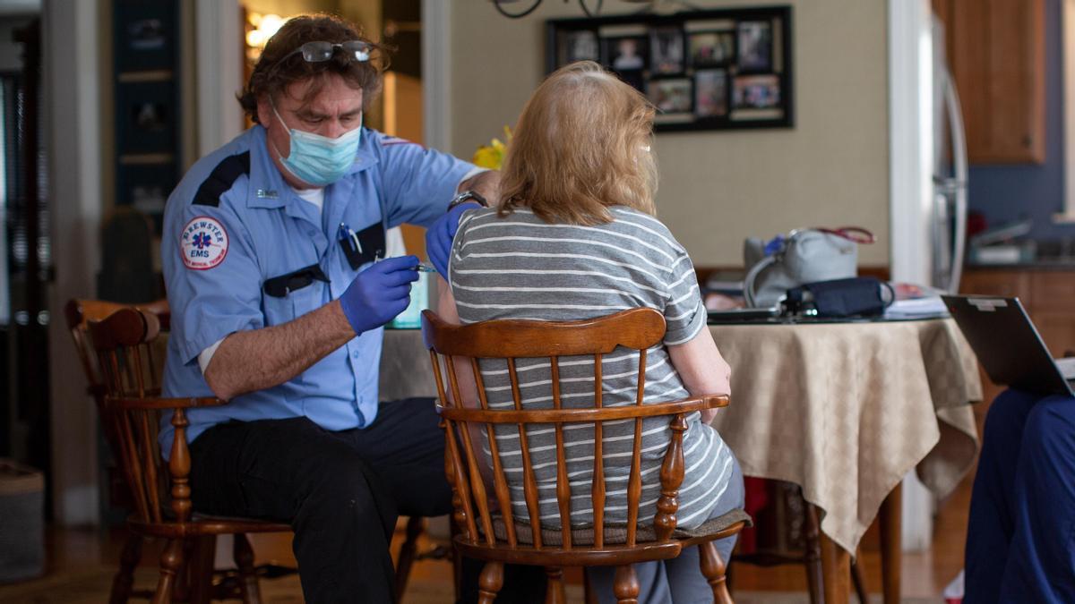 Un técnico sanitario vacuna a una mujer en su casa en EEUU.