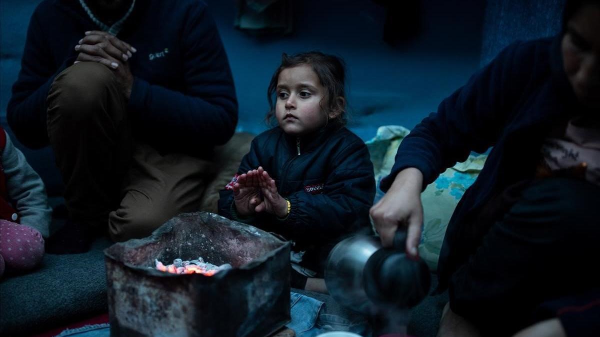 Marjan Hosini, de 3 años, calienta sus manos sobre el carbón caliente en su refugio temporal en un asentamiento improvisado junto al campamento de Moria, en Lesbos.