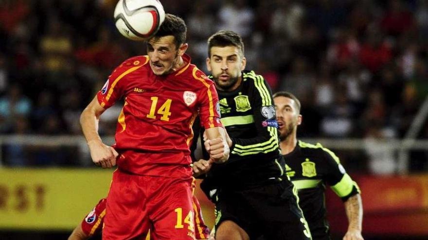 Gerad Piqué salta con el macedonio Ristevski, con Sergio Ramos detrás. // Reuters
