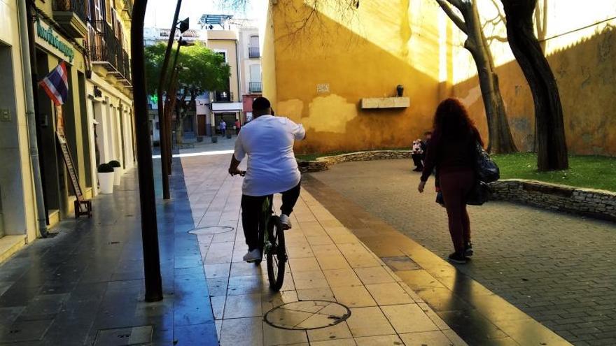 Un vecino circula en bicicleta por una calle peatonal hablando por el móvil, lo que está prohibido.