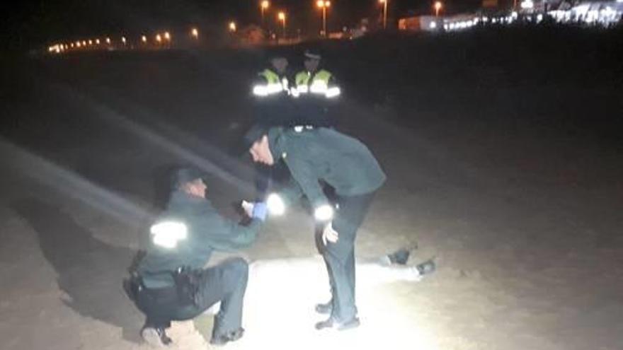 Dos agents observen el cadàver trobat al Palmar.