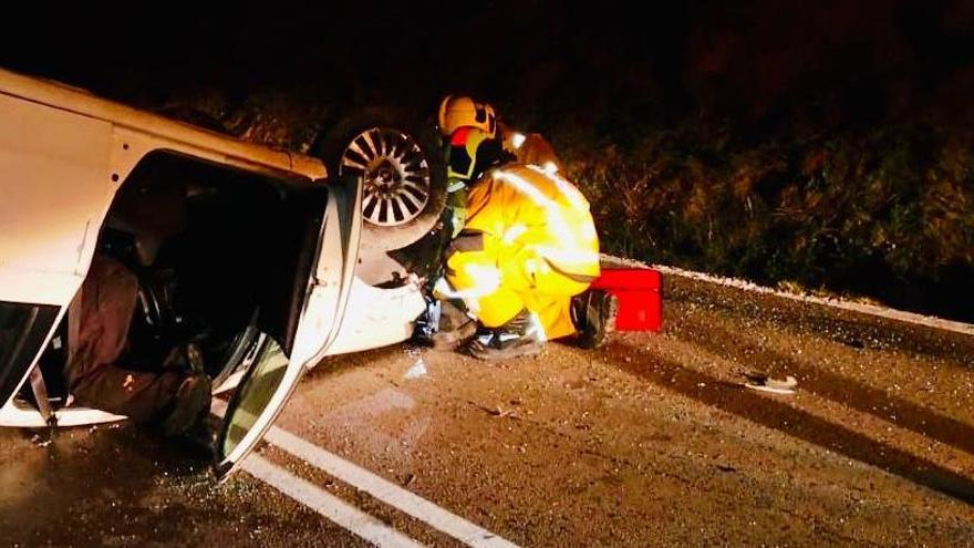 Un bombero junto al coche volcado en medio de la calzada