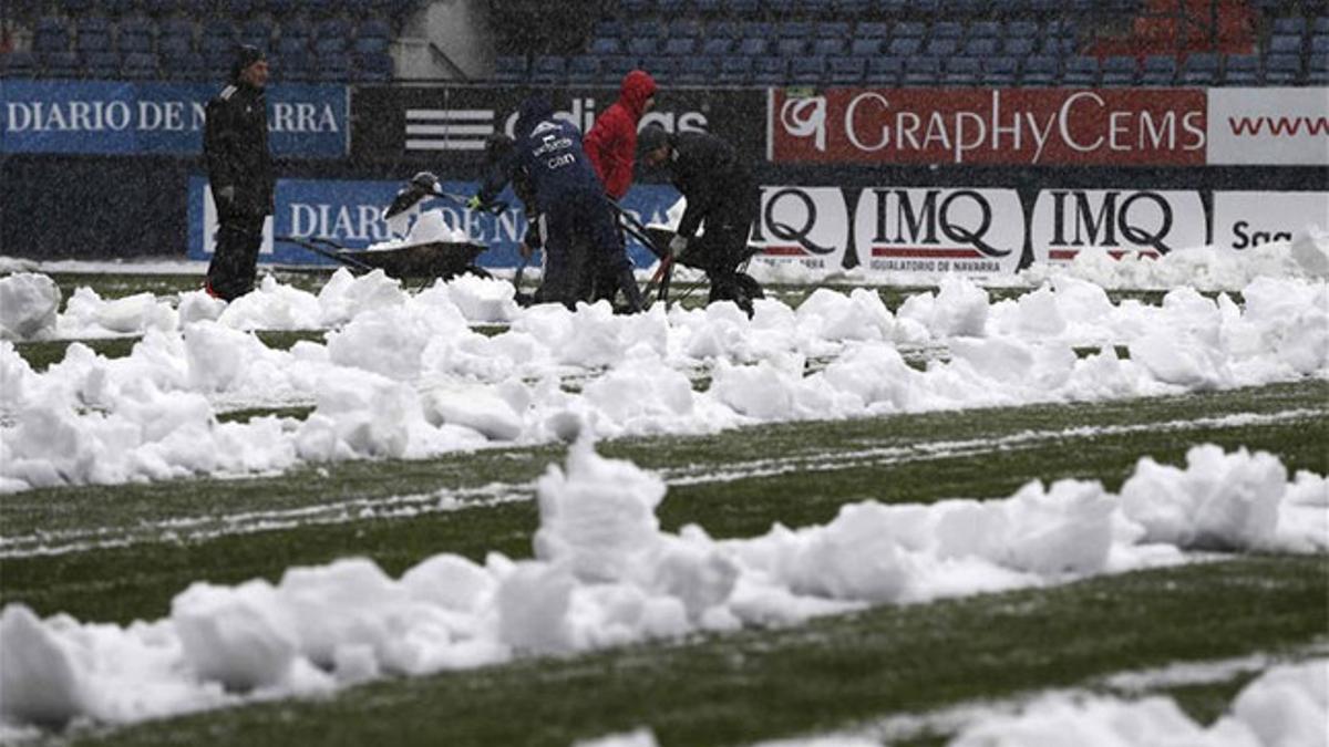 Trabajadores de Osasuna retiran la nieve acumulada en el terreno de juego de El Sadar dos horas antes del partido